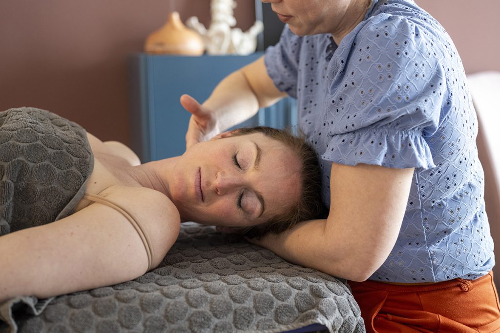Woman receiving relaxing neck massage at a spa, therapist in blue shirt providing gentle treatment.