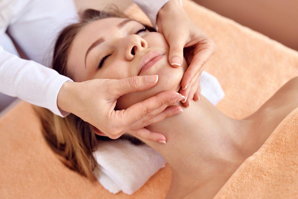 Woman receiving a relaxing facial massage at a spa, promoting wellness and skincare.