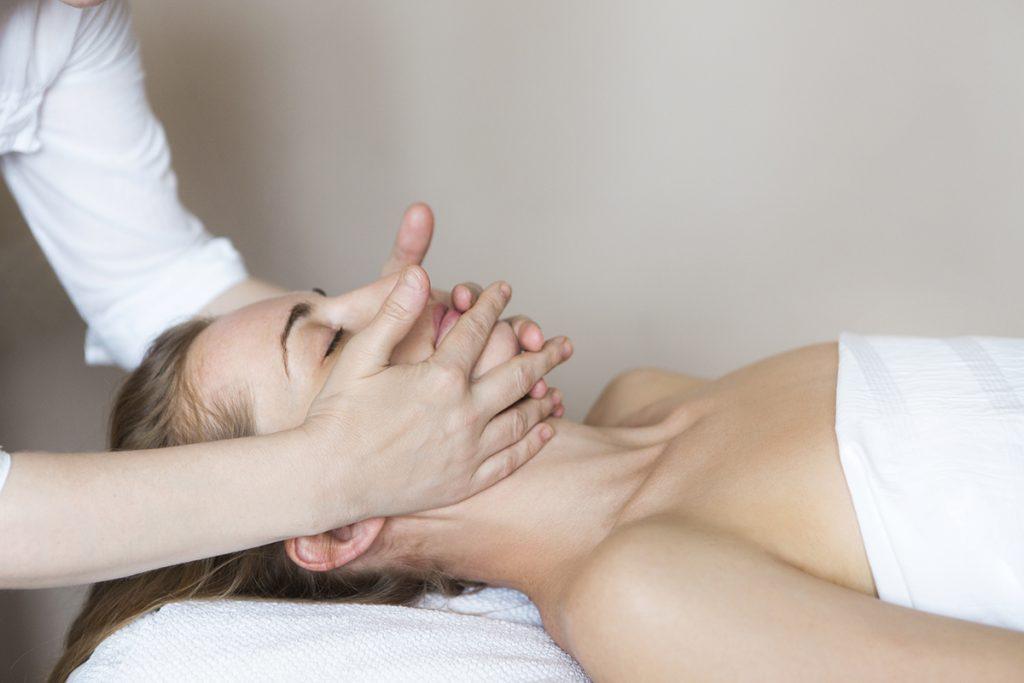 Woman receiving a relaxing facial massage at a spa, promoting self-care and wellness in a calming environment.