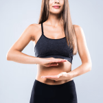 Woman in black sportswear performing a mindful meditation pose against a gray background.