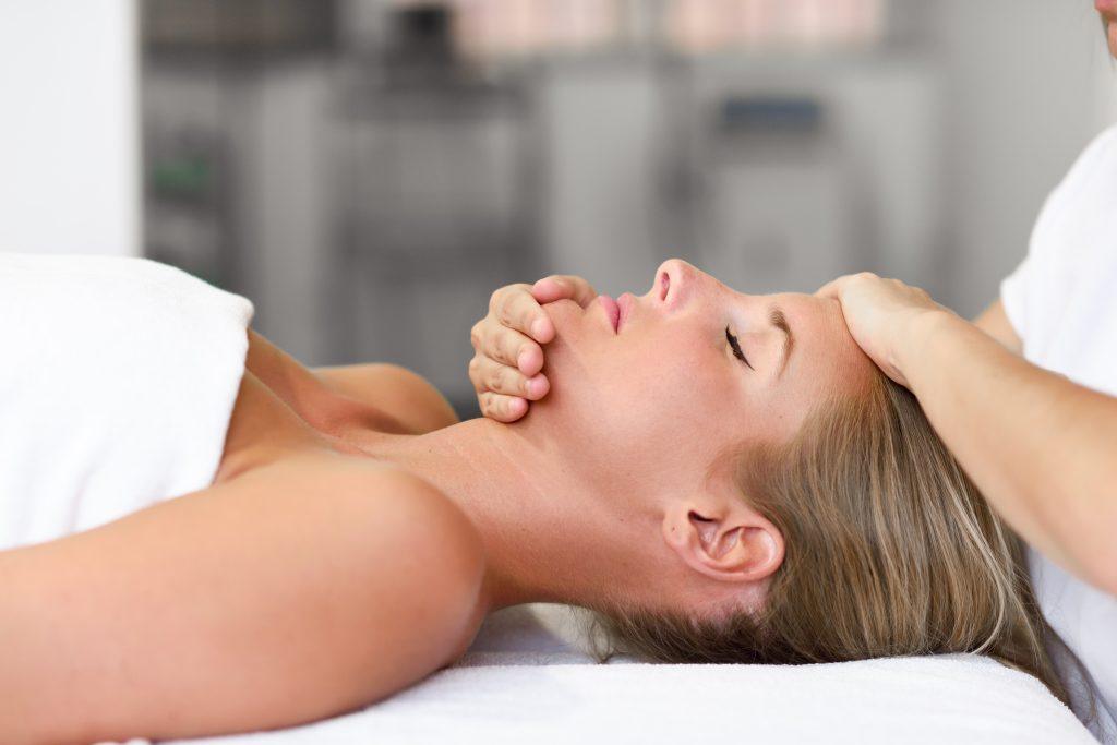Woman receiving a relaxing facial massage at a spa, promoting wellness and rejuvenation.