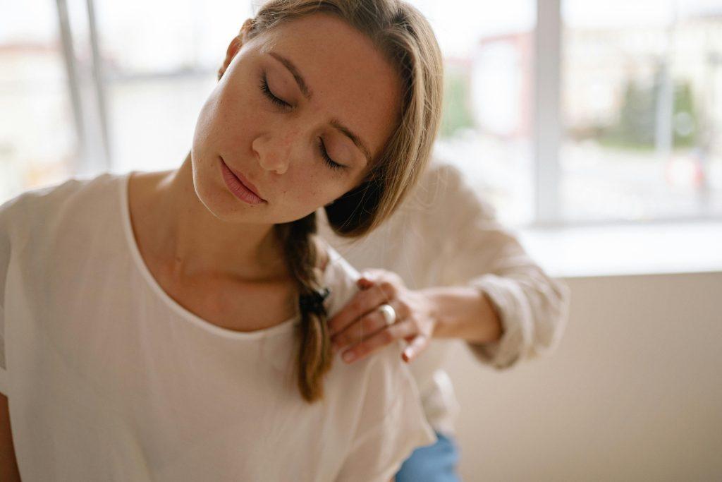 Woman receives relaxing shoulder massage in a bright room.