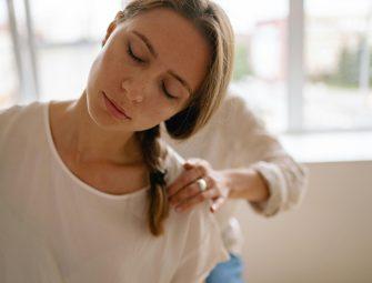 Woman receives relaxing shoulder massage in a bright room.