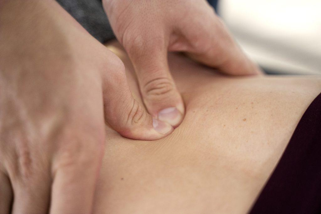 Close-up of hands performing deep tissue massage on bare back, promoting relaxation and muscle relief.