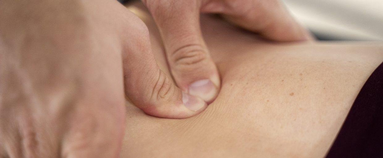 Close-up of hands performing deep tissue massage on bare back, promoting relaxation and muscle relief.