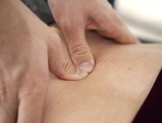 Close-up of hands performing deep tissue massage on bare back, promoting relaxation and muscle relief.
